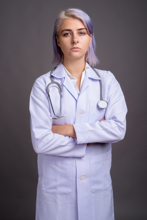 Young beautiful woman doctor with short colorful hair against grの写真素材