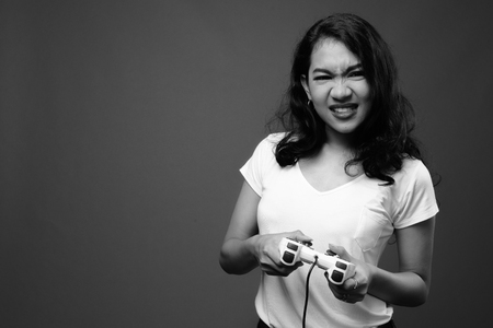 Beautiful Asian woman playing games and holding game controllerの写真素材