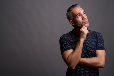 Handsome Persian man with gray hair thinking and looking upの写真素材