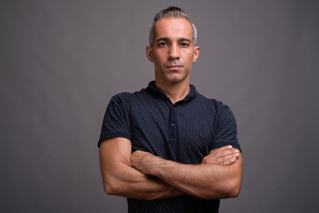 Handsome Persian man with gray hair against gray backgroundの写真素材