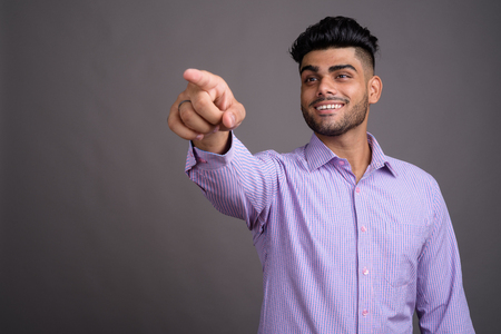 Young handsome Indian businessman against gray backgroundの写真素材