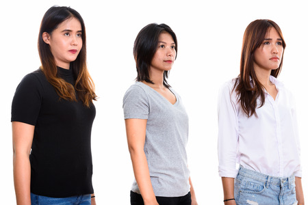 Studio shot of three young Asian woman friends thinkingの写真素材