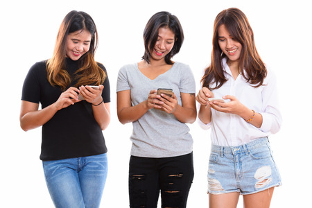 Studio shot of three happy young Asian woman friends smiling whiの写真素材