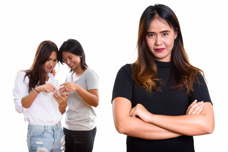 Young Asian woman with arms crossed with two happy friends at thの写真素材
