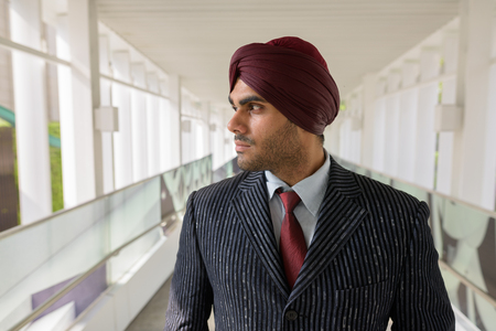 Portrait of Indian businessman with turban thinking outdoors in cityの写真素材