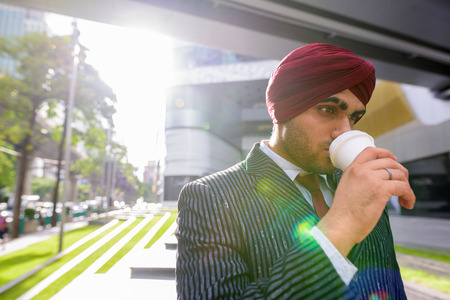 Indian businessman with turban outdoors in city drinking coffeeの写真素材