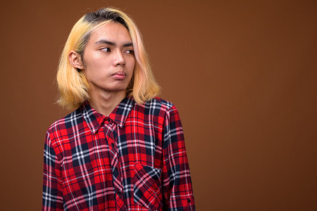 Young Asian man wearing stylish clothes against brown backgroundの写真素材