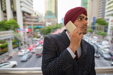 Indian businessman with turban outdoors in city talking on phoneの写真素材