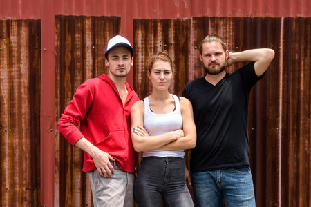 Group of friends posing together against old rusty sheet wall