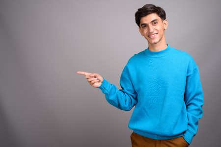 Young happy Persian teenage boy smiling and showing copyspace