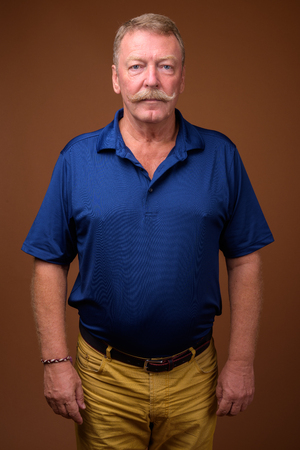 Handsome senior man with mustache against brown backgroundの写真素材
