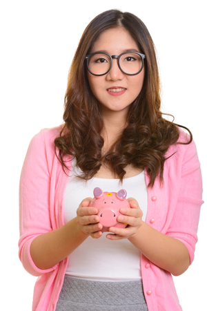 Young happy Asian woman holding piggy bankの写真素材