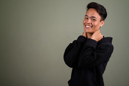 Young handsome Indian man wearing hoodie against colored backgroの写真素材