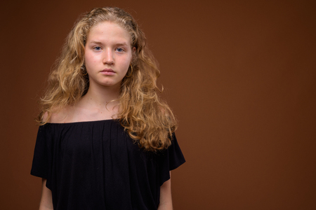 Young beautiful blonde teenage girl against brown backgroundの写真素材