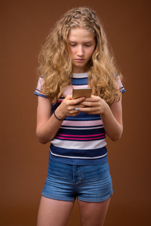 Young beautiful blonde teenage girl texting with mobile phoneの写真素材