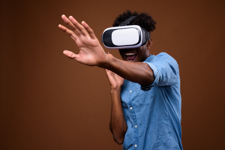 African man enjoying virtual reality while using VR glassesの写真素材