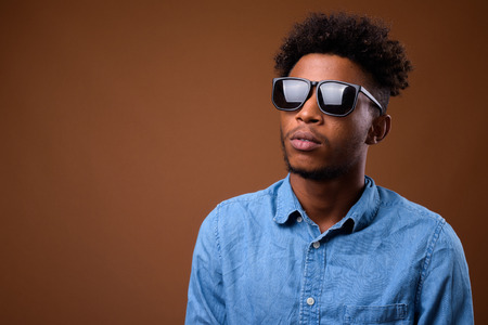Young handsome African man thinking against brown backgroundの写真素材
