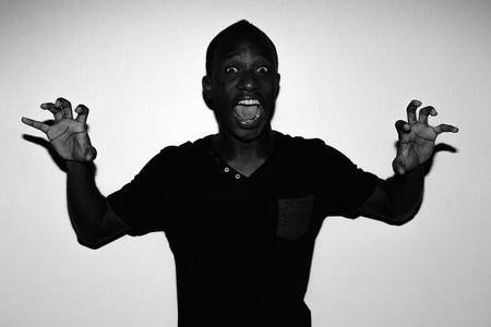Studio shot of young African man wearing black shirt against white background in black and whiteの写真素材