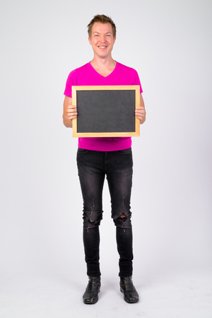 Full body shot of happy young handsome man smiling while holding blackboardの写真素材