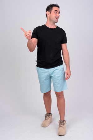 Full body shot of happy handsome man smiling while pointing fingerの写真素材