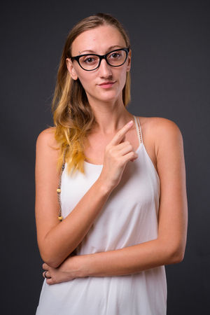 Young beautiful woman with straight blond hair against gray backの写真素材