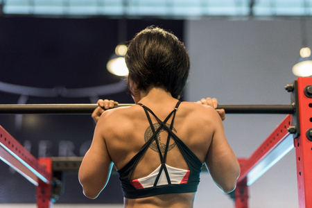 Young beautiful Asian woman doing pull up at gym
