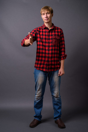 Full length portrait of young man standing against gray backgroundの写真素材