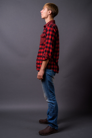 Full length portrait of young man standing against gray backgroundの写真素材