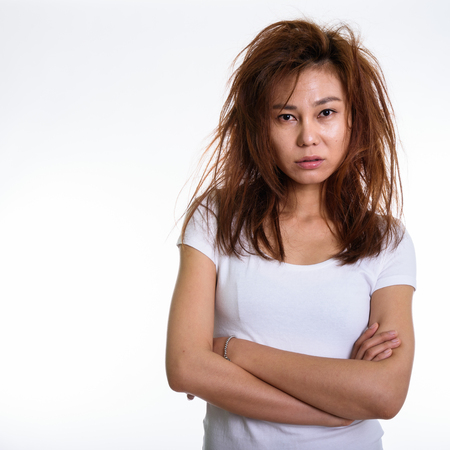 Studio shot of young Asian woman with arms crossed and messy hairの写真素材