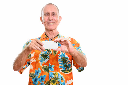 Studio shot of happy senior man smiling while taking picture