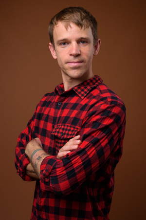 Man wearing red checkered shirt against brown backgroundの写真素材