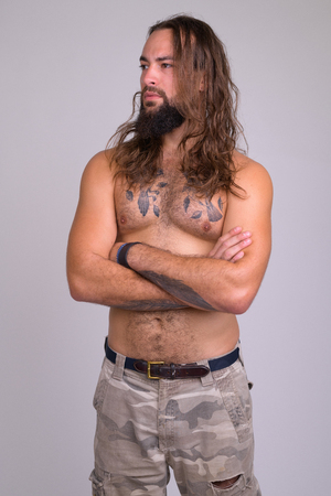 Portrait of bearded young handsome man with long hair thinking shirtlessの写真素材