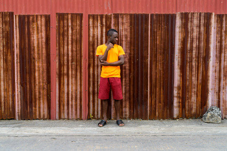 Young black African man thinking and looking down while standingの写真素材