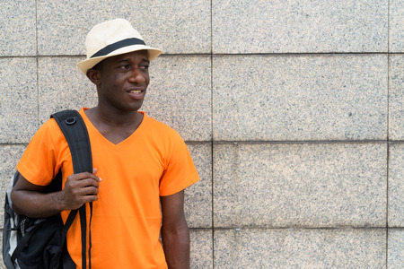 Young black African tourist man holding backpack while thinkingの写真素材