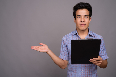 Portrait of young Asian businessman against gray backgroundの写真素材