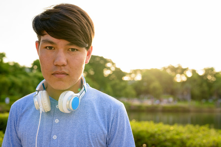 Young Asian teenage boy wearing headphones while relaxing at theの写真素材