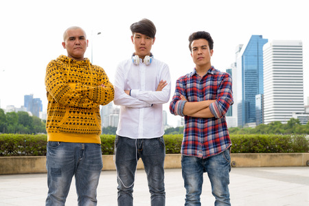 Three young Asian men relaxing at the park together