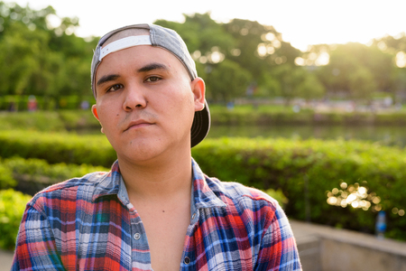 Young Asian man wearing cap while relaxing at the park in Bangkoの写真素材