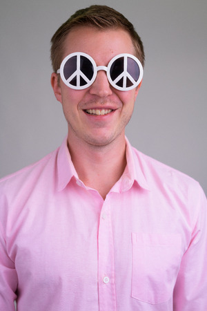 Face of young happy businessman wearing sunglasses with peace signの写真素材