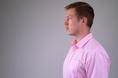 Profile view of young handsome businessman wearing pink shirtの写真素材