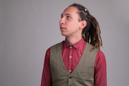 Face of young handsome businessman with dreadlocks thinking