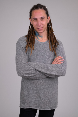 Portrait of happy young man with dreadlocks smiling while crossing arms