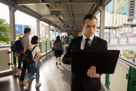 Young businessman using laptop computer in cityの写真素材