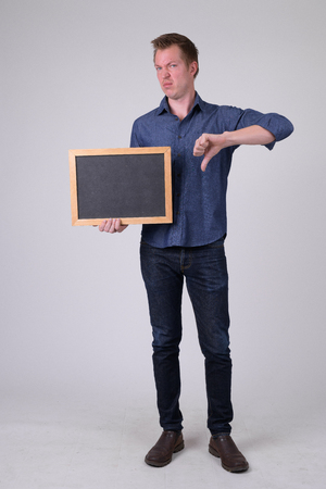 Young businessman holding blackboard and giving thumbs downの写真素材