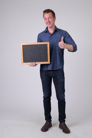 Happy young businessman holding blackboard and giving thumbs upの写真素材