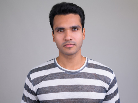 Portrait of young handsome Indian man looking at camera