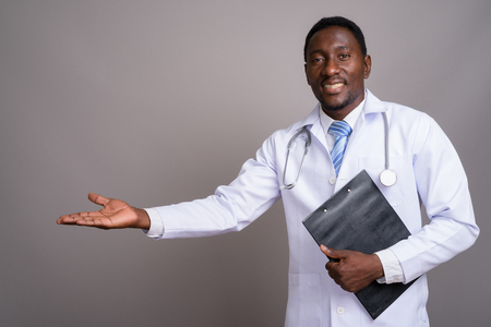 Young handsome African man doctor against gray backgroundの写真素材