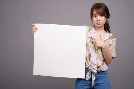 Asian woman holding empty white board with copyspaceの写真素材