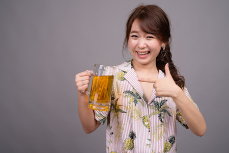 Young beautiful Asian tourist woman holding glass of beerの写真素材