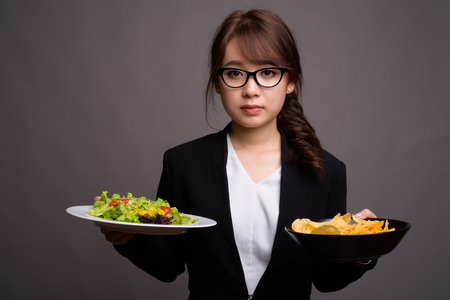 Asian businesswoman holding salad and potato chipsの写真素材